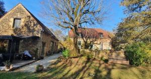 een stenen huis met een boom in de tuin bij La Closerie De Sarlat in Sainte-Nathalène