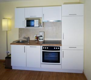 a kitchen with white cabinets and a stove top oven at Landhaus Sonnenzauber in Oberau