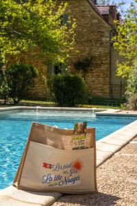 a shopping bag sitting next to a swimming pool at La Closerie De Sarlat in Sainte-Nathalène