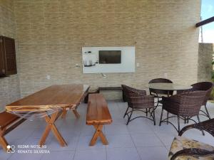 eine Terrasse mit einem Tisch und Stühlen sowie einem TV in der Unterkunft Taíba Downwind House in São Gonçalo do Amarante