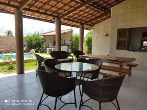 une terrasse avec une table, des chaises et une piscine dans l'établissement Taíba Downwind House, à São Gonçalo do Amarante