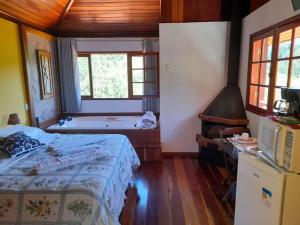 a bedroom with a bed and a tub in a room at Pousada Kalanchoê in Visconde De Maua