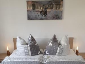 2 almohadas en una cama con una foto de ciervo en la pared en Ferienwohnung "Waldzauber" en Bärenstein