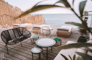 eine Terrasse mit Stühlen und Tischen sowie eine Couch und das Meer in der Unterkunft Hôtel Oasis Dakhla in Ad-Dakhla