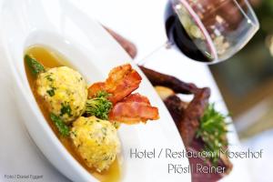 un plato de comida con carne y patatas y una copa de vino en Hotel Moserhof, en Scena