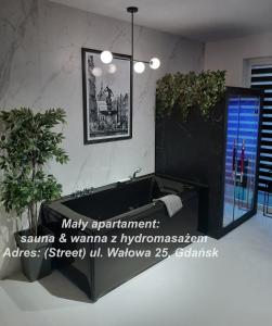 ein Wohnzimmer mit einem Sofa und einer Topfpflanze in der Unterkunft Jacuzzi Apartamenty Gdańsk - RELAX Apartments in Danzig