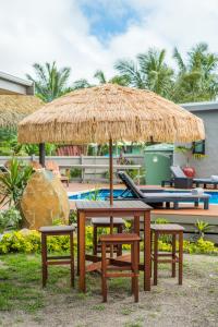 a picnic table and chairs under a straw umbrella at Cook Islands Holiday Villas - Turangi Lagoon in Muri