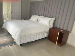 um quarto com uma grande cama branca e uma mesa de madeira em Casa da Flores Port Edward RSA em Port Edward