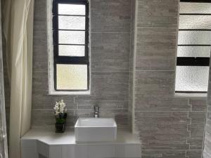 uma casa de banho com um lavatório branco e uma janela em Casa da Flores Port Edward RSA em Port Edward