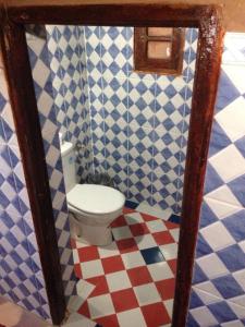 uma casa de banho com um WC em azulejos azuis e brancos em Chegaga Nomad Camp em El Gouera