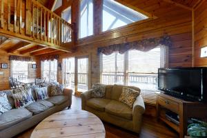 a living room with couches and a flat screen tv at Chalet of Dreams in Pigeon Forge