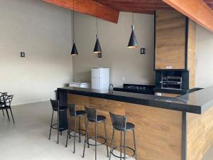 a kitchen with a counter with bar stools at Casa De Temporada Eldorado 2 in Olímpia