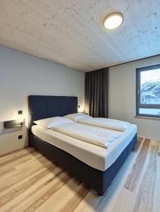 ein großes Bett in einem Schlafzimmer mit Fenster in der Unterkunft Blue Note Apartments in Schoppernau