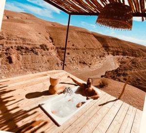 ein Holztisch mit Sonnenschirm und Waschbecken in der Unterkunft Agafay Luxury camp in Marrakesch
