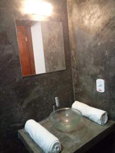 a bathroom with a sink and a mirror and towels at Pousada Tarkna in Teresópolis