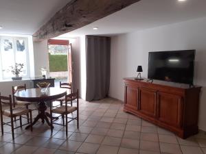 a dining room with a table and a flat screen tv at DANS LA MAISON D'A COTE in Azerables