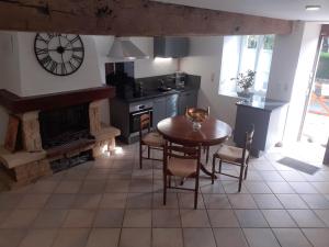 a kitchen with a table and a clock on the wall at DANS LA MAISON D'A COTE in Azerables