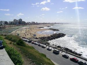 a beach with cars parked on a road next to the ocean at La Perla Moderno 2 Amb a 100 mts del Mar in Mar del Plata