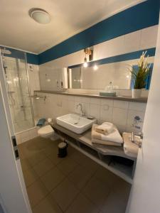 La salle de bains est pourvue d'un lavabo, d'une douche et d'un miroir. dans l'établissement Pension Wernicke-Das-Original, à Berlin
