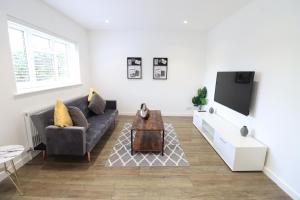 uma sala de estar com um sofá e uma televisão em Detached Bungalow - Sleeps 8 - Free Parking, Fast Wifi, Smart TV and Garden by Yoko Property em Northampton