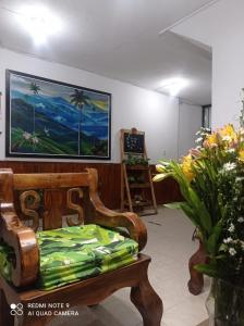 een kamer met een stoel met bloemen en een schilderij aan de muur bij Hotel Plaza Calarcá in Calarcá