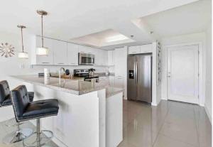 a white kitchen with a counter and a refrigerator at Bahia Mar Solare Tower 6th floor Bayview Condo 2bd 2ba with Pools and Hot tubs in South Padre Island