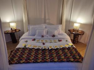 Una cama grande con sábanas blancas y flores. en Chigüa Glamping, en Ráquira