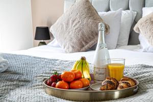 - un plateau de fruits et une bouteille de champagne sur le lit dans l'établissement Penthouse Apartment - City Centre - Free Parking, Balcony, Fast Wifi and Smart TV with Netflix by Yoko Property, à Milton Keynes