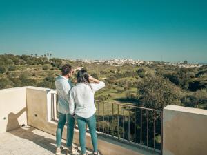 un homme et une femme debout au-dessus d'un balcon dans l'établissement Relais Terre di Romanello, à Noto