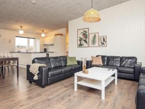 ein Wohnzimmer mit einem schwarzen Ledersofa und einem Tisch in der Unterkunft 14 person holiday home in Glesborg in Glesborg