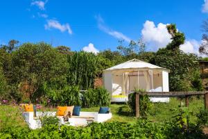 a gazebo in a garden with white furniture in the grass at Chigüa Glamping in Ráquira
