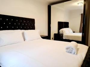 a bedroom with a large white bed and a mirror at Modern & Spacious - Walk to London ExCEL- Parking in London