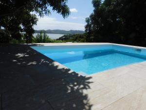 a blue swimming pool with a view of the water at Villa KANEPICE in La Trinité