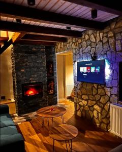a living room with a stone fireplace and a tv at Mount House Mavrovo in Mavrovo