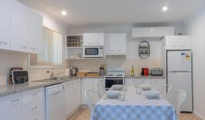 a white kitchen with a table and chairs in it at Misty Glen Cottage in Pokolbin
