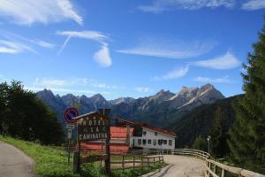 a sign in front of a building with mountains in the background at HG Hotel La Caminatha in Val di Zoldo