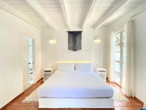 een witte slaapkamer met een groot bed met witte lakens bij Hotel Cala Blanca Cuernavaca in Cuernavaca