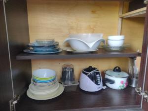 a shelf with plates and cups and dishes on it at Maxim Apartment in Pantai Cenang