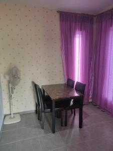 una mesa y sillas en una habitación con cortinas moradas en Maxim Apartment en Pantai Cenang