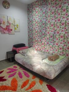 1 dormitorio con 1 cama con papel pintado de flores en Maxim Apartment, en Pantai Cenang