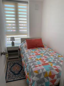 a bedroom with a bed with a colorful comforter and a window at Caupolican 243 in Valdivia