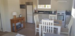 una pequeña cocina con mesa, mesa y sillas en Incline Cottage en Upper Hutt