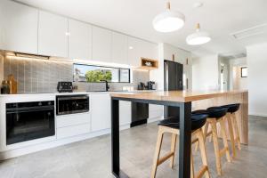 a kitchen with white cabinets and a wooden island with bar stools at Beach Walk on Alfred in Bridport