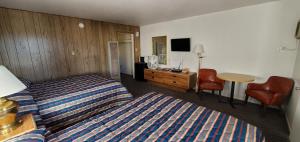 a hotel room with two beds and a table and chair at Budget Inn Motel Gallup in Gallup