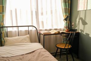 a bedroom with a bed and a desk with a book at Hostel Niniroom in Kyoto