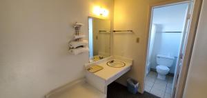 a bathroom with a sink and a mirror and a toilet at Budget Inn Motel Gallup in Gallup