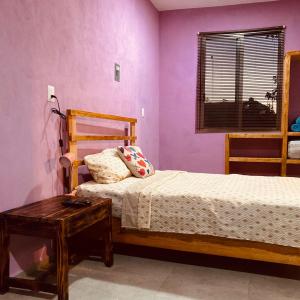 una camera da letto con pareti viola, un letto e un tavolo di Almendrita Habitación I a Bacalar