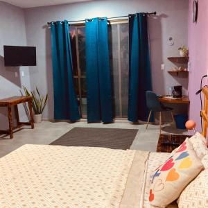 una camera da letto con tende blu, un letto e una scrivania di Almendrita Habitación I a Bacalar