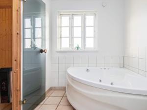 a white bathroom with a tub and a window at 8 person holiday home in Aabenraa in Løjt