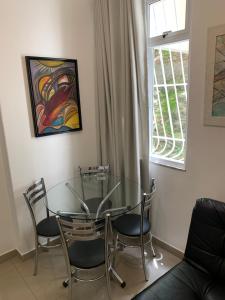 einen Glastisch und Stühle in einem Zimmer mit Fenster in der Unterkunft Adolfo Paiva Apartment in Rio de Janeiro